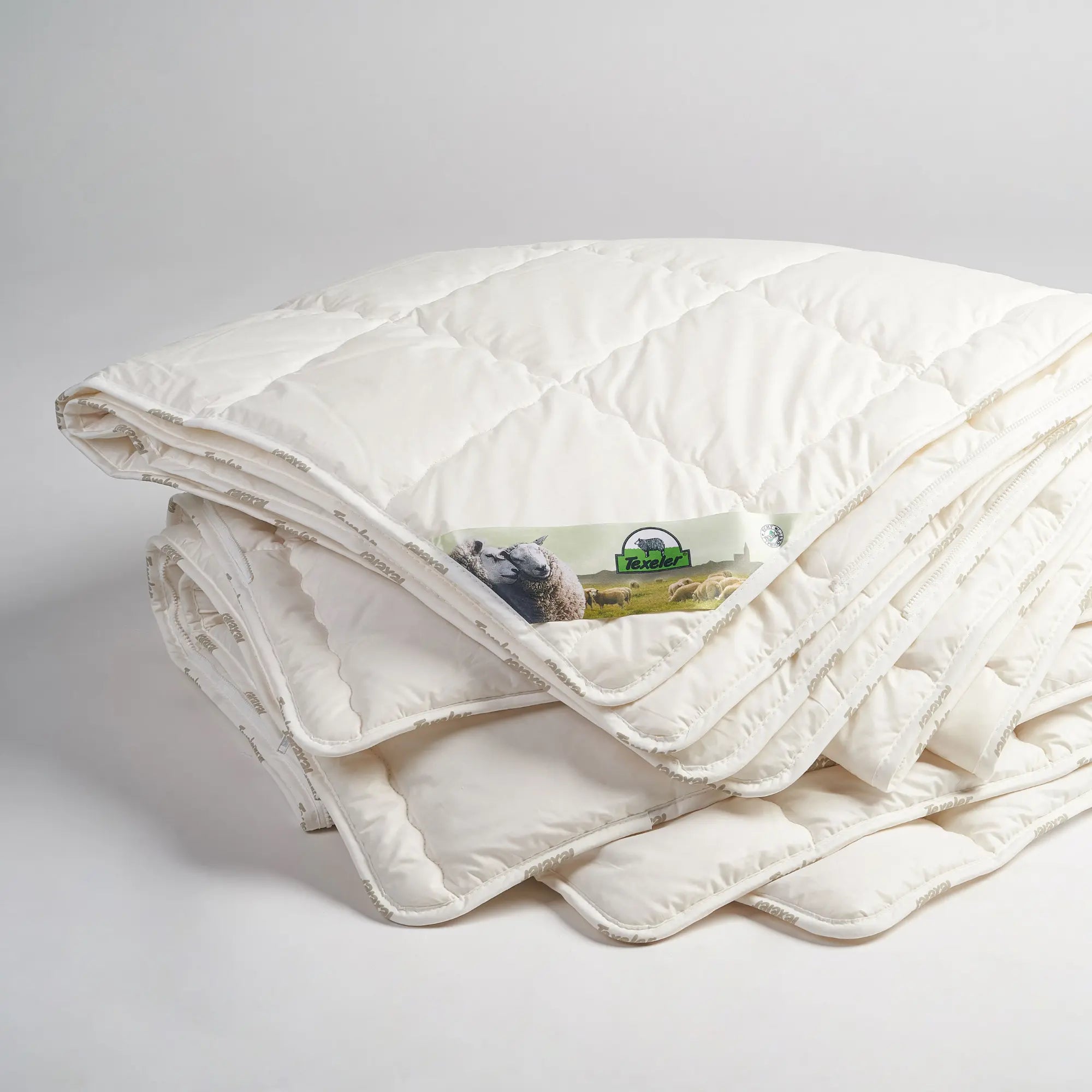 the two layers of the texeler pure nature perkal wool comforter with cotton cover laid on top of eachother with the label clearly visible